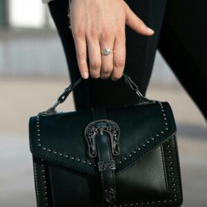 A woman holding a black handbag with studs